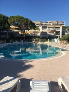 a swimming pool with two white chairs and a building at French Riviera Deluxe near Nice airport in Cagnes-sur-Mer