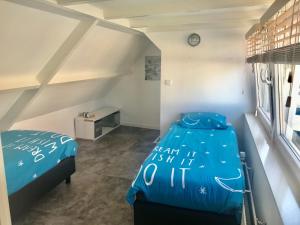 a bedroom with a bed with a blue comforter at Ferienhaus Glücklich am Meer 1 mit Wellnesszugang in Egmond aan Zee