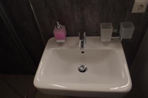 a white sink in a bathroom with a pink candle at Hotel & Gasthaus Zum Eichenkranz in Luckenwalde