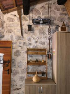 a kitchen with a stone wall with a shelf and a refrigerator at Etno House Ivanovic in Virpazar