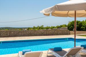 uma piscina com duas cadeiras e um guarda-sol em Llucasaldentet em Alaior