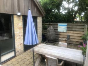 an umbrella on a patio with a bench at Texelduinen59 in De Koog