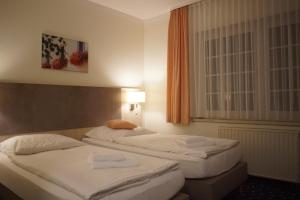 two beds in a hotel room with at Hotel & Gasthaus Zum Eichenkranz in Luckenwalde
