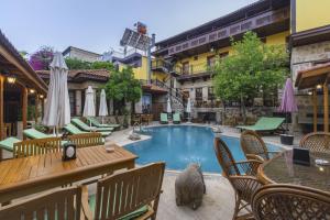 a pool with chairs and a table and a cat sitting next to it at La Paloma Hotel in Antalya