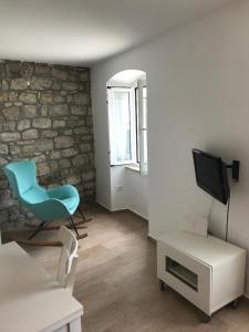ein Wohnzimmer mit einem blauen Stuhl und einem TV in der Unterkunft Apartment Pogled na luku II in Cres