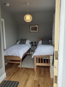 a bedroom with two beds and a chandelier at Black Stair Cottage in Helensburgh