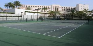 un campo da tennis di fronte a un edificio di Crowne Plaza Sohar, an IHG Hotel a Sohar