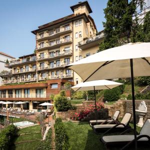um hotel com cadeiras e guarda-sóis em frente em Hotel Resort & Spa Miramonti em Rota d'Imagna