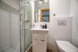 a white bathroom with a sink and a shower at Apartament Stary Mlyn in Zakopane
