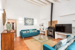 uma sala de estar com sofás azuis e uma televisão em Llucasaldentet em Alaior