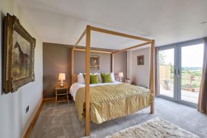 a bedroom with a canopy bed with a large window at Harrogate Barns in Harrogate