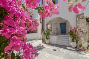 ein weißes Haus mit rosa Blumen davor in der Unterkunft Honey & Cinnamon Luxury Suite in Naxos Chora