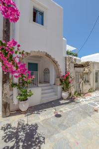 ein weißes Haus mit rosa Blumen davor in der Unterkunft Honey & Cinnamon Luxury Suite in Naxos Chora