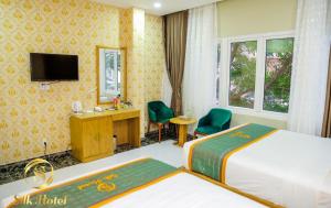 a hotel room with two beds and a television at Silk Hotel near Tan Son Nhat Airport in Ho Chi Minh City