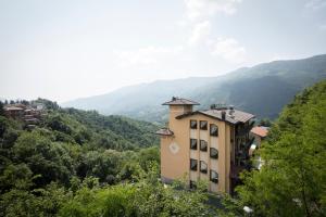 um edifício numa colina com montanhas ao fundo em Hotel Resort & Spa Miramonti em Rota d'Imagna