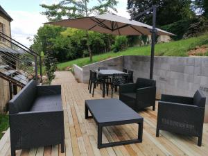 un patio con tavoli, sedie e ombrellone di chambres d’hôte le breuil a Sarlat-la-Canéda