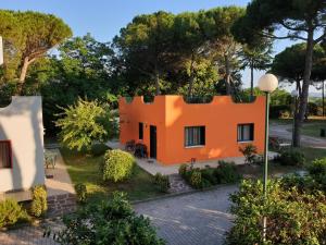 pomarańczowy dom z drzewami w tle w obiekcie Villaggio Mithos w mieście Misano Adriatico