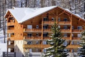 a large wooden building with a snow covered roof at Les Terrasses de Labrau in La Foux
