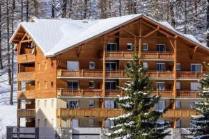 un grand bâtiment en bois avec un toit couvert de neige dans l'établissement Les Terrasses de Labrau, à La Foux