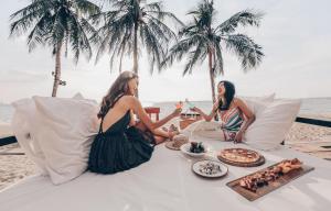 two women sitting on a table on the beach with food at Pullman Pattaya Hotel G - SHA Extra Plus in Pattaya North