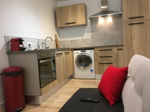 Una cocina con lavadora y una almohada roja. en Studio hyper centre, proche gare, entrée indépendante, en Valence
