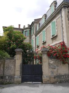 a black gate in front of a house with red flowers at Villa BeauSoleil in Digne-les-Bains +2 photos