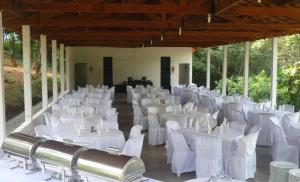 a banquet hall with white tables and white chairs at Pousada Encanto da Mata - Ecológica in Caconde