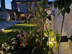 a garden with flowers next to a wall at Rooms & Apartment STELIO in Loborika