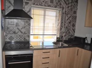 a kitchen with a stove and a sink and a window at Casa Flora T1 - Vila do Bispo in Vila do Bispo