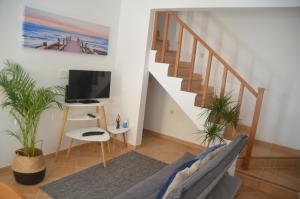 a living room with a staircase and a tv at Casa Flora T1 - Vila do Bispo in Vila do Bispo