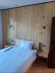 Schlafzimmer mit einem weißen Bett und Holzwänden in der Unterkunft Родопчани Старцево in Starzewo