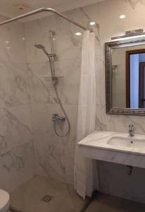ein Bad mit einer Dusche, einem Waschbecken und einem Spiegel in der Unterkunft Родопчани Старцево in Starzewo