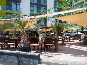 Studio Alezzi Beach Resort في مامايا نورد نافورداي: فناء في الهواء الطلق مع طاولات وكراسي وأشجار