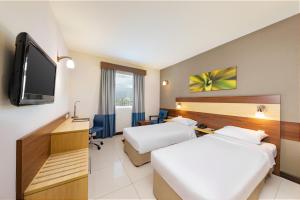 a hotel room with two beds and a flat screen tv at Citymax Sharjah in Sharjah