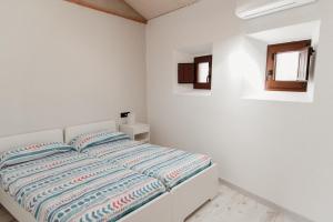 a white bedroom with a white bed and a window at Casa Rural Turgalium in Trujillo