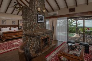 - un salon avec une cheminée en pierre et un lit dans l'établissement Ngorongoro Oldeani Mountain Lodge, à Oldeani