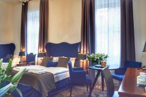 een slaapkamer met een bed en blauwe stoelen en ramen bij Shalom Kazimierz in Krakau