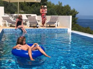 a woman sitting on an inner tube in a swimming pool at Apartments Magdalena in Račišće
