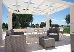 a patio with a white pergola with a table and chairs at Trullo Maddy in Cisternino