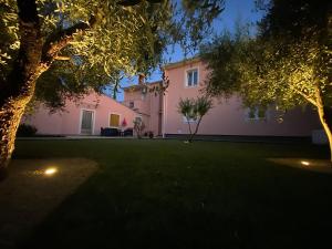 ein rosafarbenes Haus mit grünem Hof in der Nacht in der Unterkunft Apartments Prodan in Fažana