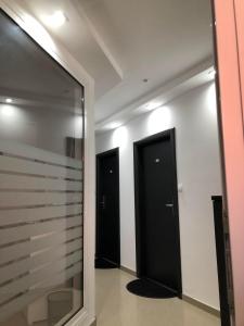 een hal met twee zwarte deuren en een spiegel bij Apartmani Jovanovic in Ivanjica