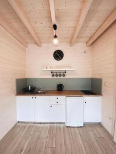 a kitchen with white cabinets and a clock on the wall at Nad Rozlewiskiem in Bobolin