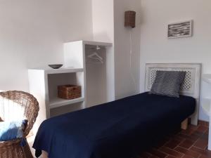 una camera con un letto blu e una sedia di T2 rénové 100m plage avec SPA privatif entre calvi et ile rousse a Lumio