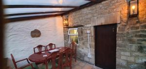 uma sala de jantar com mesa e cadeiras e uma parede de tijolos em Quirky Cottage - Dogs Welcome - Free 24 hr Cancellation's em Corsham