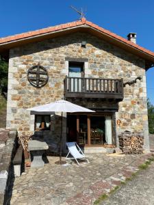 ein Steinhaus mit einem Tisch und einem Sonnenschirm in der Unterkunft llar de Cosme in Caso