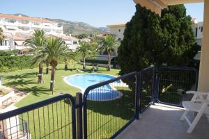 a balcony with a pool and palm trees at Apartamentos Porta Mediterranea in Alcossebre