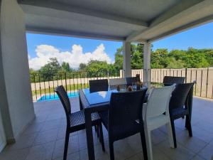 a table and chairs on a patio with a view of a pool at VILLA AMBER YourCroatiaHoliday in Drenje