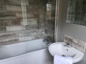 uma casa de banho com um lavatório branco e uma banheira em Harding Row em Norton