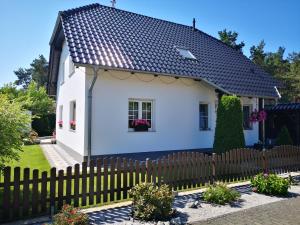 uma casa branca com um telhado preto em Gästezimmer im bewohnten EFH mit Pool und Garten em Ziltendorf
