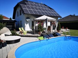 uma casa com piscina com painéis solares no telhado em Gästezimmer im bewohnten EFH mit Pool und Garten em Ziltendorf